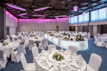 Ballsaal mit festlich dekorierten runden Tischen und einem Buffet in der Mitte des Raumes
